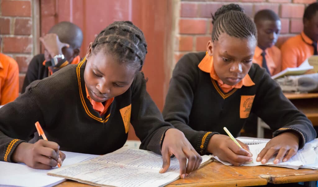A photo showing girls writing at their school desks at Hope and Faith School to illustrate our education work