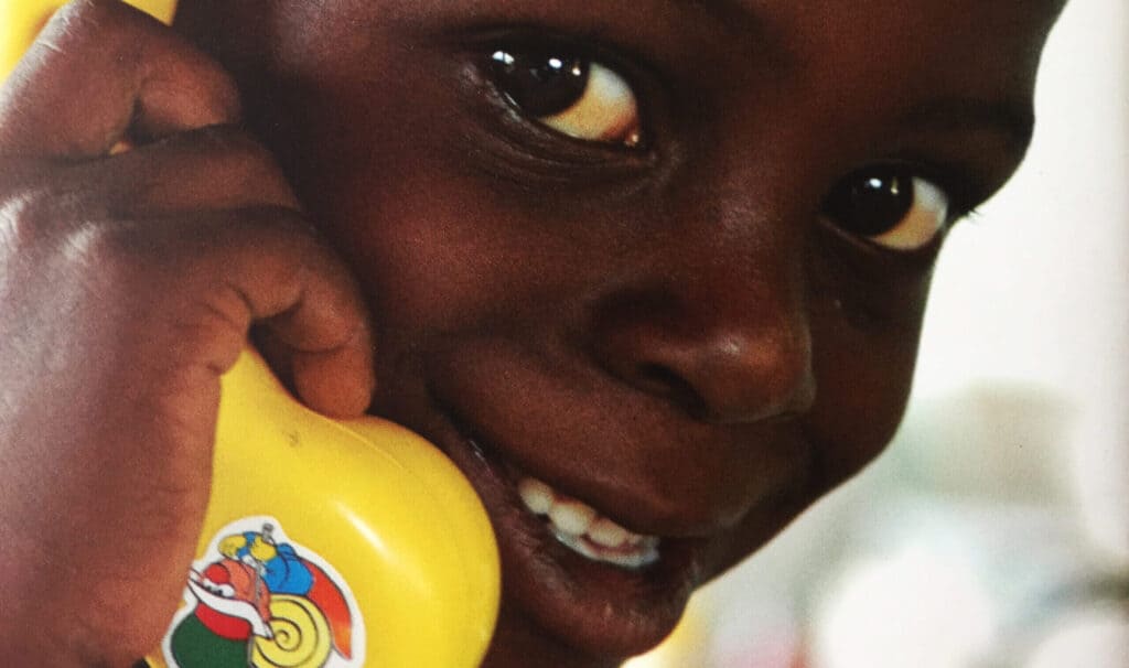 A photo of a boy on a toy telephone to illustrate getting in touch with ZOA contact details