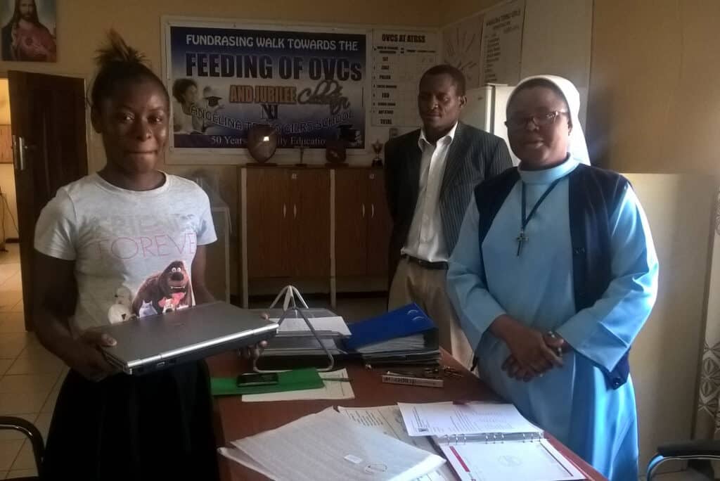 A photo showing a tertiary student receiving a refurbished computer to help with her studies